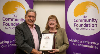 A man and a woman holding a framed certificate